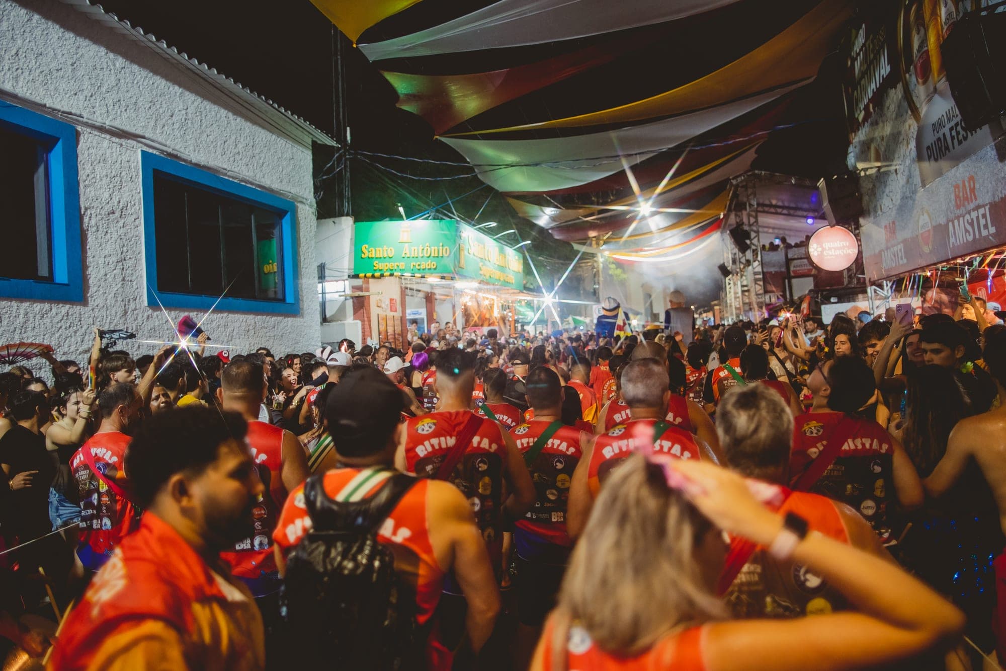 Ritmistas de costas no meio da multidão, com as marcas dos parceiros estampadas nas camisetas